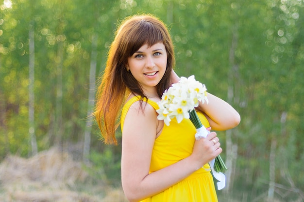 Happy young girl smiling with a bouquet of flowers outdoors