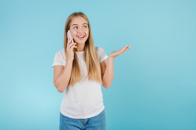 Happy young girl talking on the phone isolated over blue