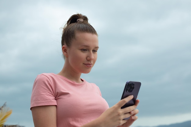 Happy young girl uses her phone on the roof of a house balcony city background woman taking selfie