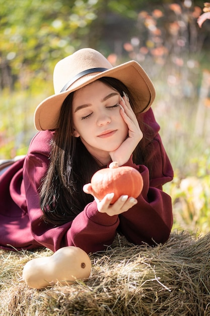 Happy young girl with pumpkin in autumn garden