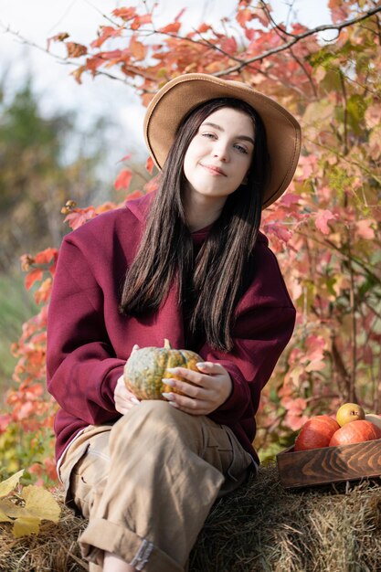 Happy young girl with pumpkin in autumn garden