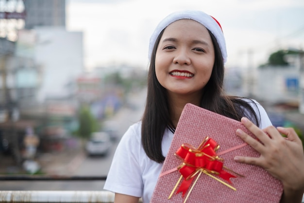 Happy young girls wear Christmas hat on city view background.