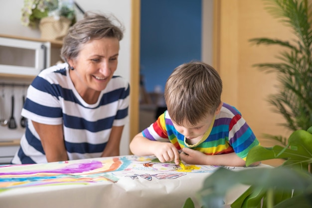 Photo happy young grandmother draw art picture playing with grandson enjoy family weekend comfortable childish room smiling granny spending time with kids early development entertainment