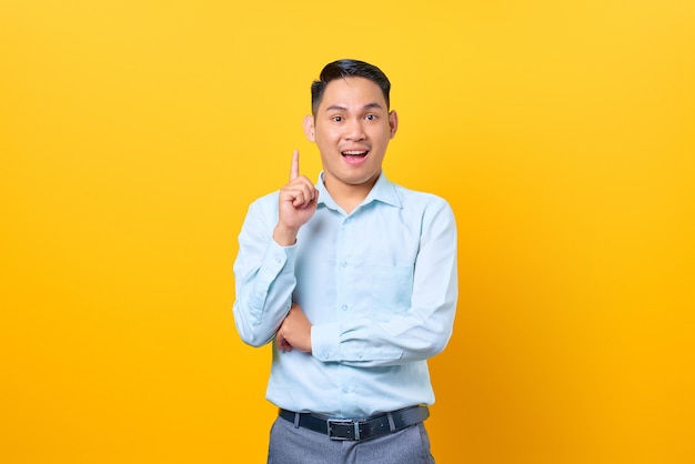 Happy young handsome businessman having a creative idea and looking camera on yellow background