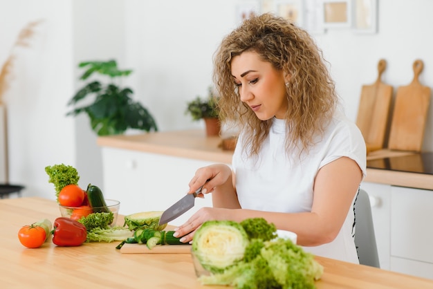 Happy young housewife mixing vegetable salad