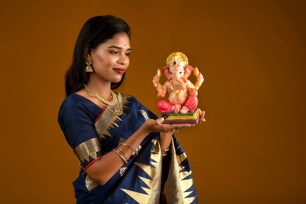 Happy young Indian woman posing with Ganesha statue on the occasion of Ganesh Festival