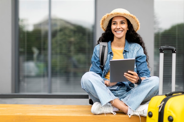 Happy young lady tourist using pad sitting on bench outdoors