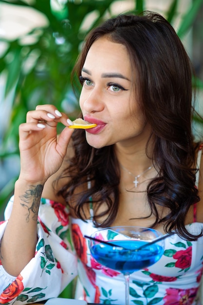 Happy young lady with a glass of cocktail in an outdoor gourmet restaurant Place for text