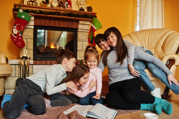 Happy young large family at home by a fireplace in warm living room on winter day