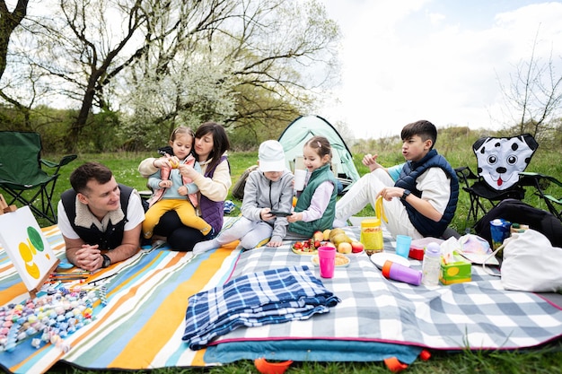 Happy young large family with four children having fun and enjoying outdoor on picnic