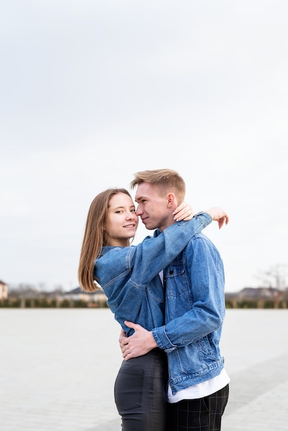 Happy young loving couple embracing each other outdoors in the park having fun