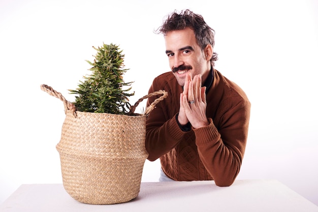 A happy young man next to a cannabis plant with white background