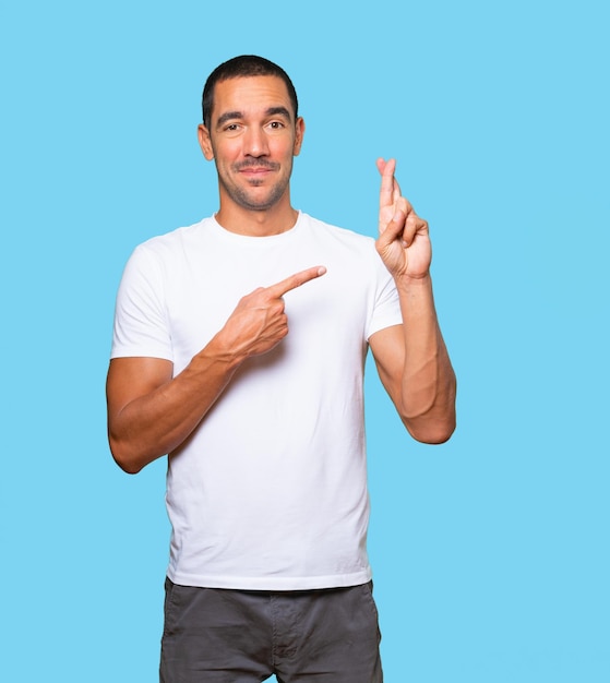 Happy young man doing a crossed fingers gesture