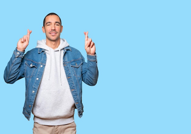 Happy young man doing a crossed fingers gesture