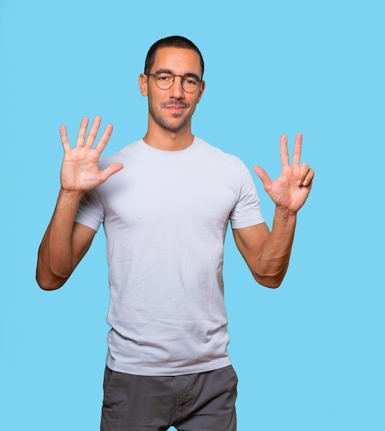 Happy young man doing a number eight gesture with his hands