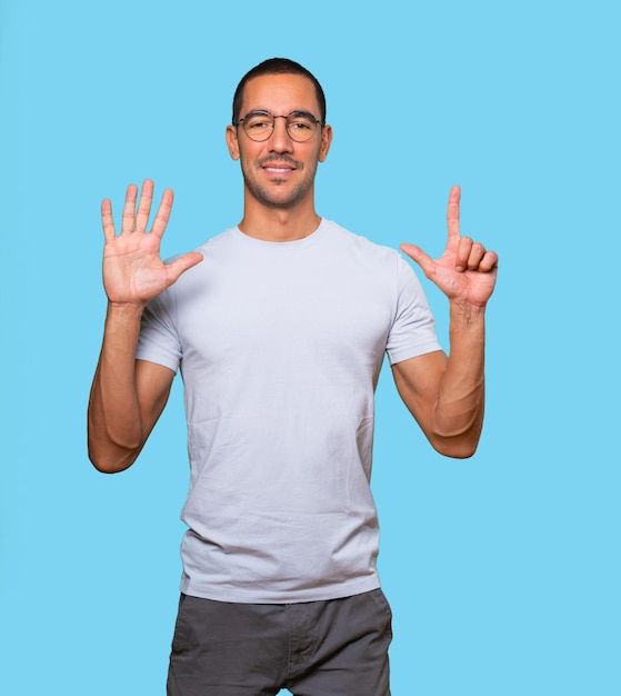 Happy young man doing a number seven gesture with his hands