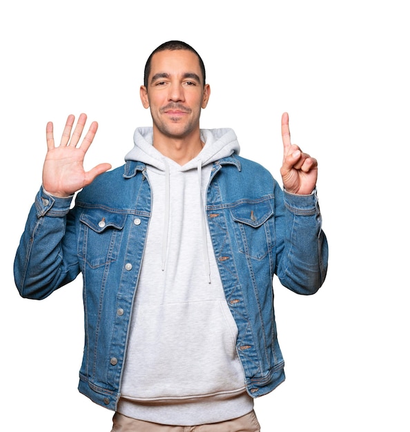 Happy young man doing a number six gesture with his hands