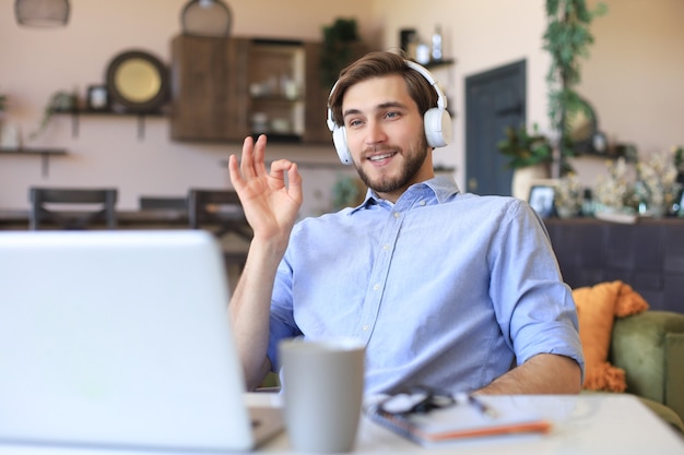 Photo happy young man in earphones working from home during self isolation.