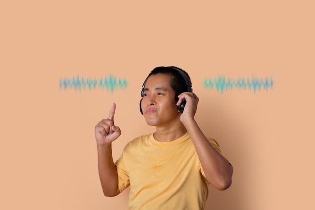 Happy young man in headphones listening to music and dancing with sound waves