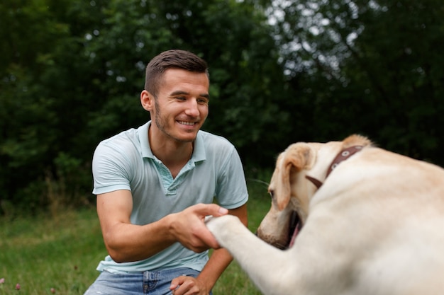 Happy young man holding a paw of a Labrador