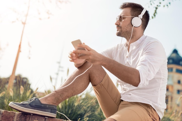 Photo happy young man listening to music on a smart phone