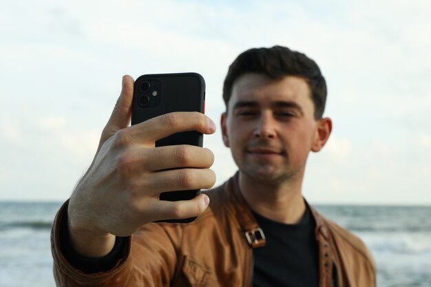 Happy young man making selfie against sea