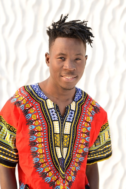 Happy young man in Nigerian national clothes on a white wall