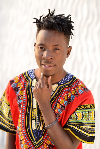 Happy young man in Nigerian national clothes on a white wall