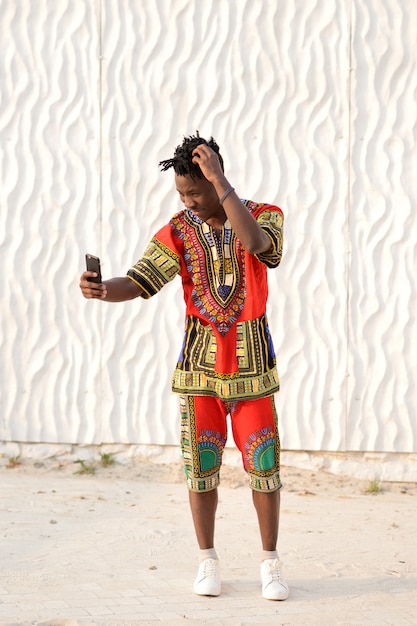 Happy young man in Nigerian national clothes on a white wall