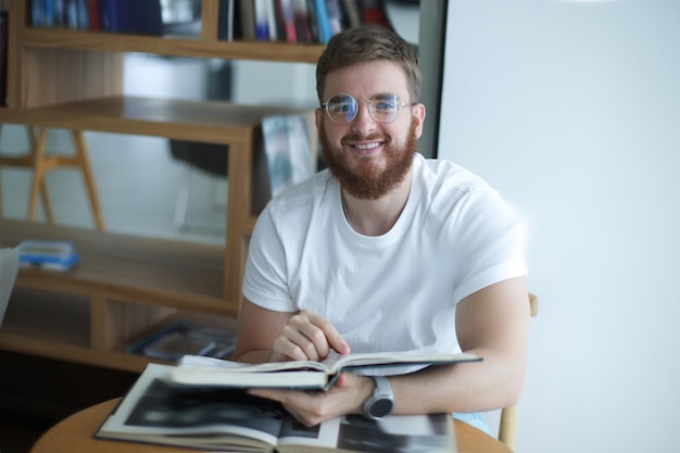 Happy young man read book in library college or university student prepare to exam in glasses and