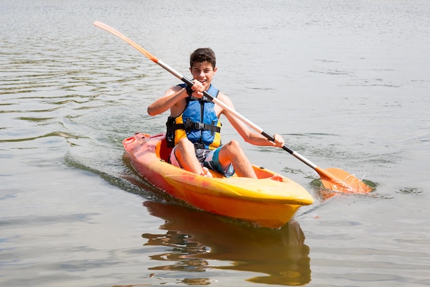 Happy young man rowing on lake in kayak and smiling