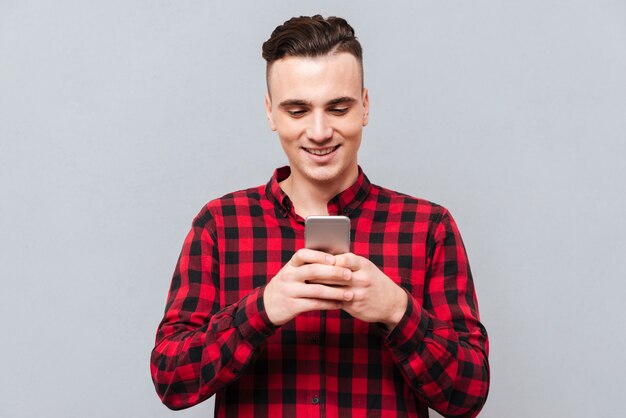 Happy young Man in shirt writing message on phone.