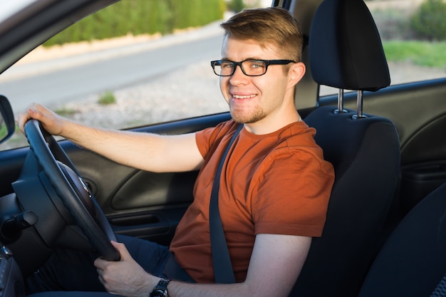 Happy young man sitting in the car and smiling.