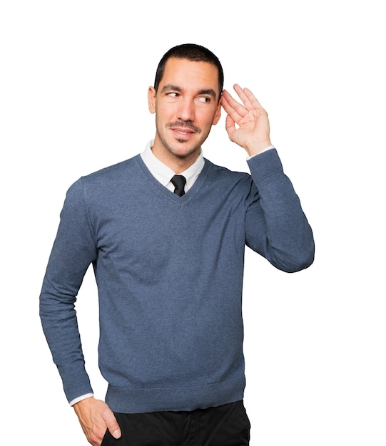 Happy young man smiling and making a gesture of trying to hear something