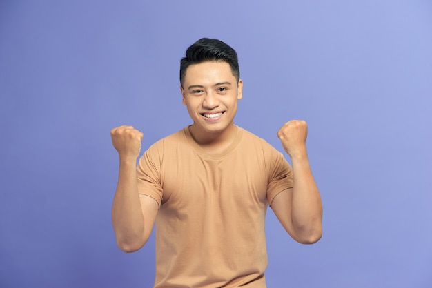 Happy young man smiling while standing on a blue background