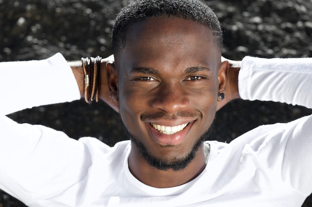 Happy young man smiling with hands behind head