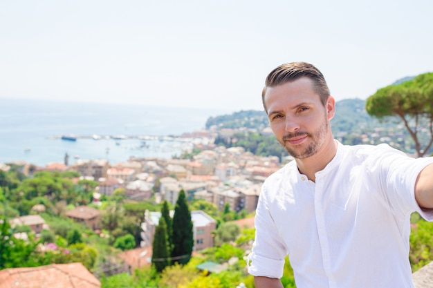 Happy young man taking selfie on the old coastal town Rapallo in Liguria