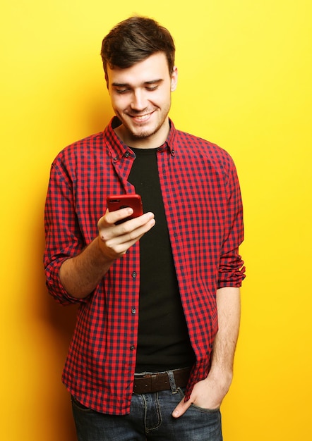 Happy young man talking on cell phone over yellow background