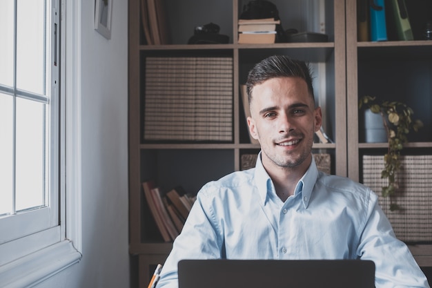 Happy young man teenager smiling and talking in video conference studying and learning online with school. Millennial doing homework at home calling