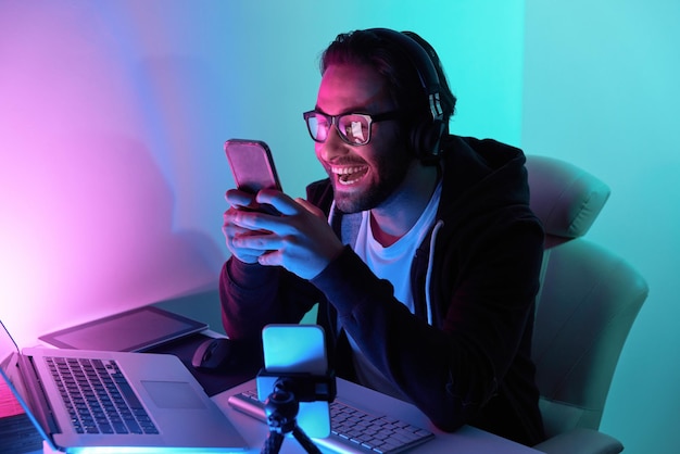 Happy young man using technologies while streaming online against colorful background