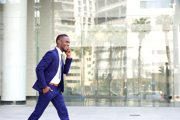 Happy young man walking and talking on mobile phone 