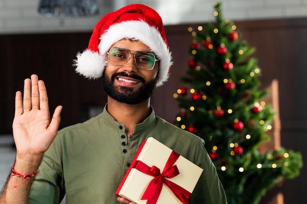 Happy young man wearing santa hat looking at camera celebrating New Year distance online party