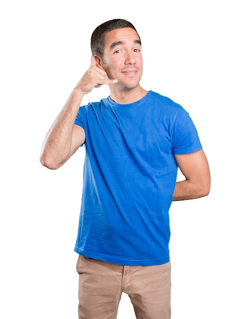 Happy young man with call gesture against white background