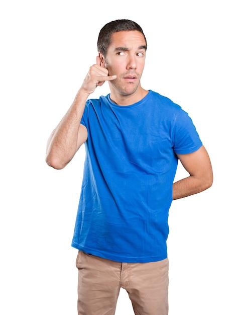 Happy young man with call gesture against white background