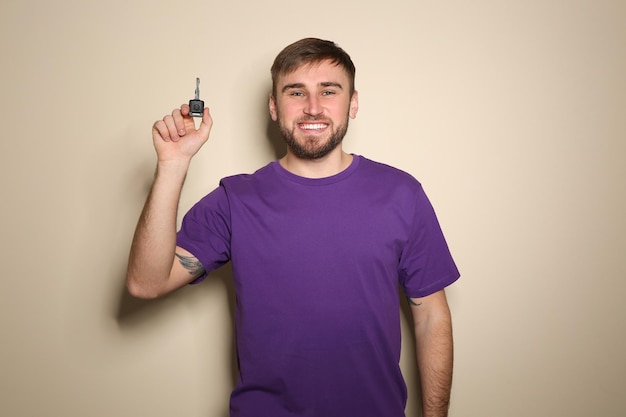 Happy young man with car key on color background Getting driving license