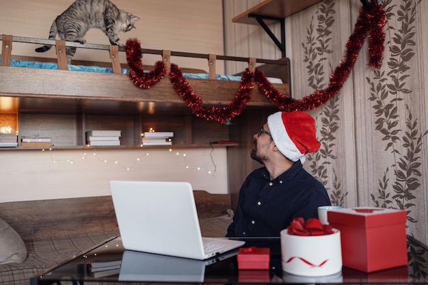 Happy young man with funny cat at home Christmas gift boxes