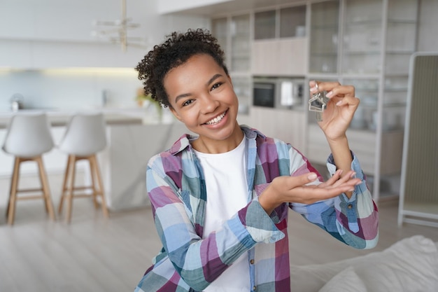 Happy young mixed race girl showing home keys at camera moved to new apartment Real estate service