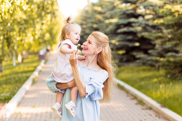 Happy young mother playing with her little baby daughter girl on sunshine