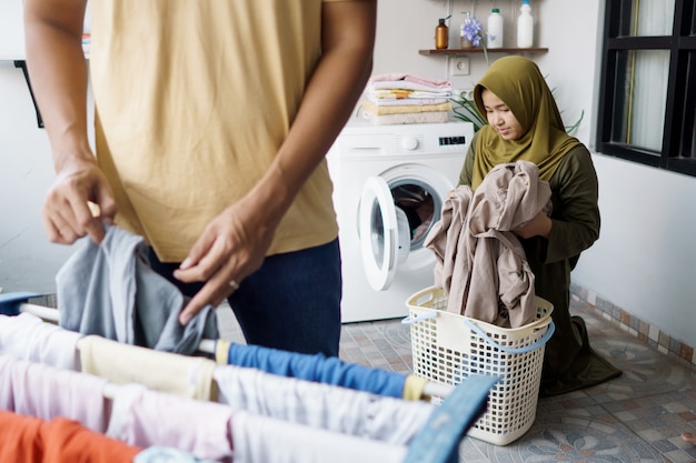 Happy young muslim woman and her husband doing laundry together at home