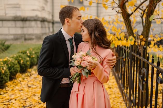 Happy young newly married wedding couple on walk in golden yellow fall autumn park near vintage atmosphere gothic cathedral.